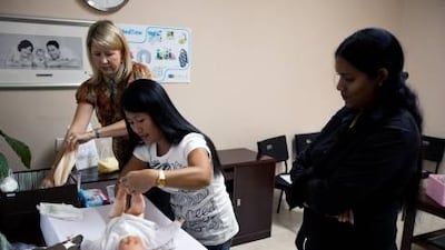 Anne Marpole, back left, a midwife at Infinity Health Clinic, teaches two nannies how to care for a newborn baby.