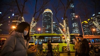 People wearing face masks walk along a street in the central business district in Beijing, on Thursday, February 2. AP