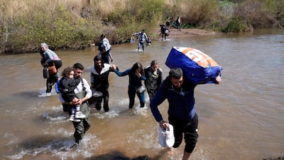 Syrian families fleeing sectarian violence in their country cross a shallow river into northern Lebanon, near the village of Heker Al Daher in Akkar province. AP
