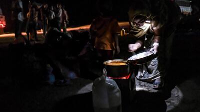 A woman refugee from the Tigray region of Ethiopia makes some food as they wait to be transferred to a camp with more infrastructure at a UNHCR reception area in the east Sudanese border village of Hamdayet in Sudan. Getty Images