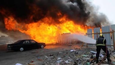 A fireman tries to extinguish a fire at wood storage area that was allegedly set ablaze by anti-F1 protesters in Tubli village, south of Manama.