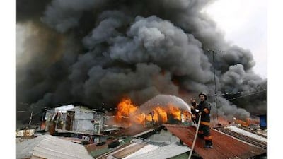 A fireman shouts and gestures for more water while working to extinguish a blaze in a neighbourhood of shanties in Manila yesterday. It was the latest in a series of fires in such neighbourhoods in the city.