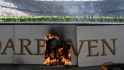 An advertising board is on fire as stewards are lined up across the pitch after the match is interrupted by fan trouble. Fabian Bimmer / Reuters