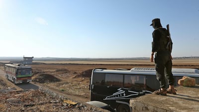 A member of Hayat Tahrir Al Sham watches a bus get ready to enter the towns of Al Fua and Kefraya to evacuate residents on July 18, 2018. AFP