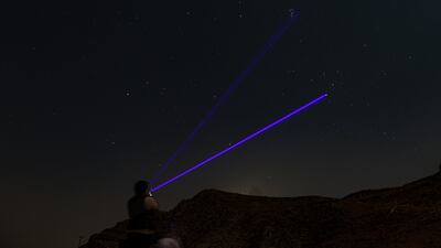 A member of the Dubai Astronomy Group uses a laser to point out where to spot the meteors