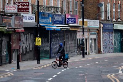 A delivery man cycles past shuttered shops along a near-deserted street in the City of London during the third coronavirus lockdown. AFP