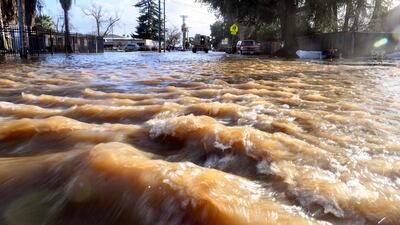 Water rushes down a street towards rescue crews as they search for stranded residents. AFP