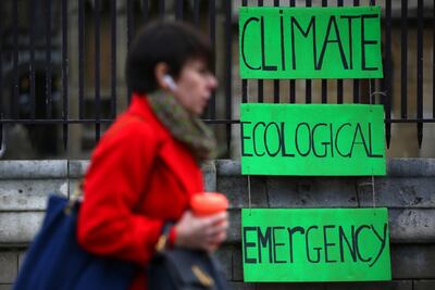 A pedestrian walks past climate protesters, holding a re-useable coffee cup on December 7, London. Getty Images