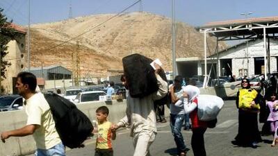 Syrian refugees cross the Lebanese border post at Al Masnaa. Nearly 19,000 Syrians, many from the capital, have fled to Lebanon since Wednesday.