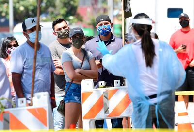 A Covid-19 test site volunteer gives directions to people waiting in line at a walk-in coronavirus test site in Los Angeles, California. AFP
