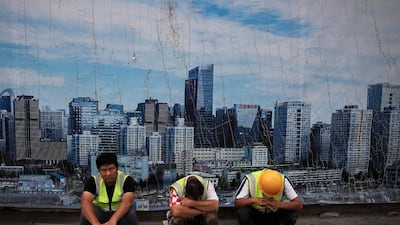 Chinese workers take a break outside a construction site wall depicting the skyline of the Chinese capital at the Central Business District in Beijing. Roughly 800 million people have been raised above the poverty line since China introduced reforms in 1978 to embrace the market economy. Andy Wong / AP