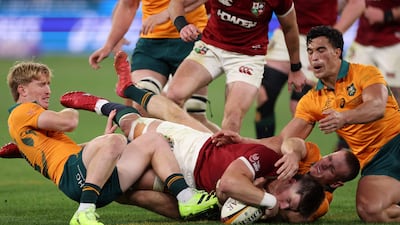Lions' Huw Jones scores a try just before half-time despite the efforts of Tate McDermott and Max Jorgensen. AFP