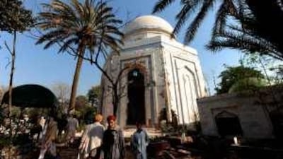 Residents walk in front of the damaged mausoleum after a bomb blast in Peshawar.