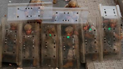 Lebanese soldiers shelter behind protective shields during clashes in Beirut with supporters of former prime minister-designate Saad Hariri, who has stepped down.