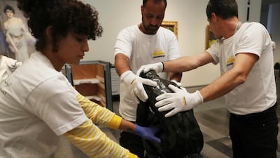 Staff members hold Rodin's 'The Thinker' bronze statue during installation at the Louvre Museum in Abu Dhabi. Kamran Jebreili / AP photo