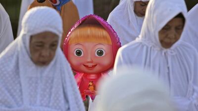 A balloon of Russian cartoon character “Masha” peeks through Musim women performing an Eid Al Fitr prayer to mark the end of the holy fasting month of Ramadan at Sunda Kelapa port in Jakarta, Indonesia. Dita Alangkara / AP photo