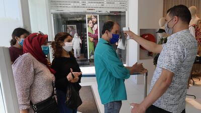 A clothing store employee measures the temperature of shoppers in the Tunisian capital Tunis. AFP