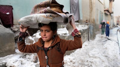 A girl carries bread on her head as she walks in the snow in Afghanistan where a humanitarian crisis is unfolding following the Taliban takeover. AP