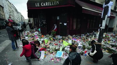 People lay flowers and candles in front of the restaurant Le Carillon, one of the establishments targeted in November's gun and bomb attacks, in Paris. Frank Augstein / Associated Press