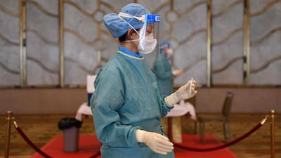 A worker in a protective suit holds a sample from a guest to test for Covid-19 in Beijing, ahead of a reception being held by Chinese leaders on the eve of China's National Day. AFP