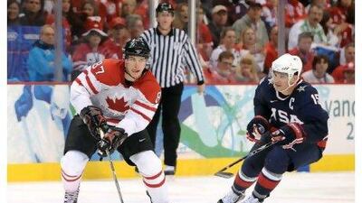 Sidney Crosby of Canada plays the puck through the neutral zone past Jamie Langenbrunner of USA during their men's gold medal game of Winter Olympics.