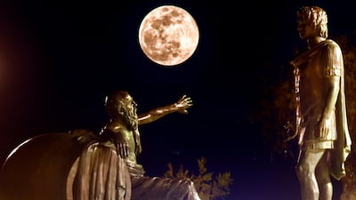 The moon rises between the statues of Alexander the Great and Diogenes of Sinope in Corinth, 83km from Athens. AFP