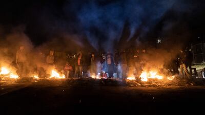 Armed community members gather around a fire to keep warm at a road block set up in Phoenix Township, North Durban, on July 15, 2021.