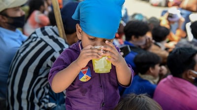 Migrant families wait to board buses going to the railway station to return by train to their hometowns after the government eased a nationwide lockdown, Ahmedabad on May 23. Sam Panthaky / AFP