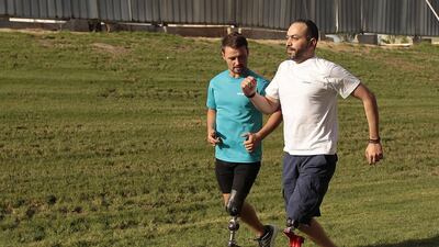 Heinrich Popow, left, trains 40-year-old Syrian Ahmed Malek during a running clinic for amputees. Jeffrey E Biteng / The National
