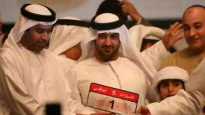 Saeed al Khouri holds his newly purchased plate number one after an auction at the Emirates Palace in February. Online auctions are drawing some surprising bids as well.
