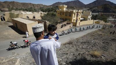 A spectator, with child, watches the peloton during the final stage of the Tour of Oman on Friday. Sebastien Nogier / EPA