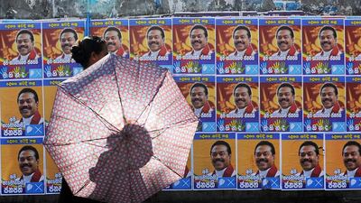 A Sri Lankan woman walks past election posters of president Mahinda Rajapakse in the Colombo suburb of Piliyandala on January 6, 2015. Mr Rajapakse faces an unprecedented challenge when he seeks re-election on Thursday. Lakruwan Wanniarachchi/AFP Photo