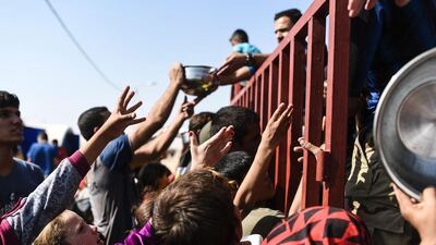 Displaced Iraqis gather to get food and aid at a refugee camp in Qayyarah south of Mosul. Bulent Kilic / AFP Photo