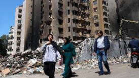 People walk past damaged buildings in Beirut after a wave of Israeli strikes. EPA