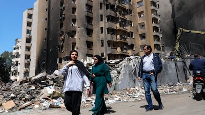 People walk past damaged buildings in Beirut after a wave of Israeli strikes. EPA