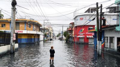 A woman is standing on a street flooded by rains caused by Tropical Storm Melissa, in Santo Domingo, Dominican Republic. Reuters