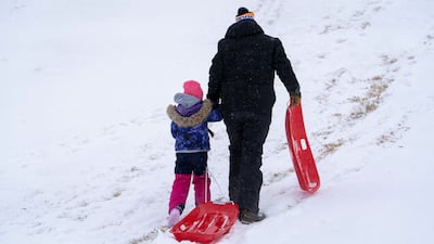JP Ritchie and his daughter Charlotte Ritchie walk up a sled hill in Oklahoma City. Reuters