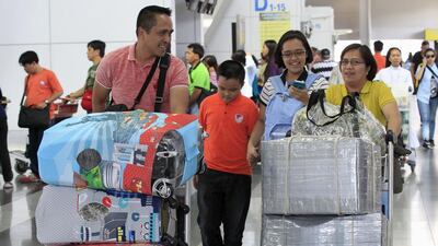 Airline passengers push carts with their baggage wrapped with plastic and cloth, which they say is to avoid falling for what they say are "bullet-planting" incidents inside Ninoy Aquino International Airport. Romeo Ranoco / Reuters