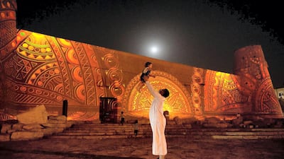 A man plays with a child in front of a light installation at Riyadh's annual light and art festival, Noor Riyadh. SPA