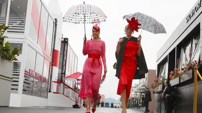 Racegoers shelter from the rain. EPA