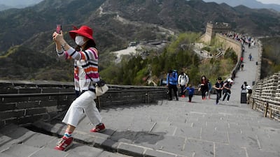 A visitor uses her mobile phone to take a picture as she climbs a steep section of the Great Wall of China in Beijing. AFP