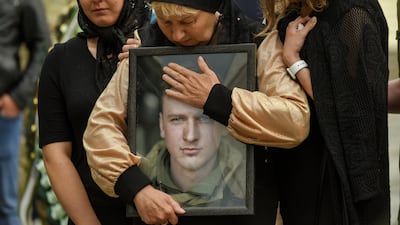 The mother of a Ukrainian serviceman holds her son's portrait during his funeral ceremony in Kyiv in 2022. EPA