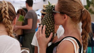 A shopper conducts the sniff test on a pineapple at an organic food and craft market on Saadiyat Island. Photo: Christopher Pike / The National