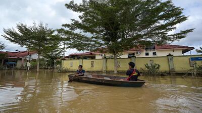 Residents ride a boat through floodwaters in Mentakab in Malaysia's Pahang state on January 8, following heavy monsoon rains. The UAE has sent aid to help those in need. Mohd Rasfan / AFP