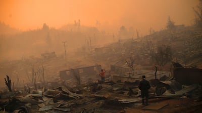 People walk amid the remains of buildings on January 26, 2017 after a forest fire in Santa Olga, 240 kilometres south of Santiago. Chile. Six people have died battling vast forest fires in central Chile, officials said Wednesday. Multiple blazes have ravaged 238,000 hectares and are growing, according to the forestry service. Pablo Vera Lisperguer / Agence France-Presse