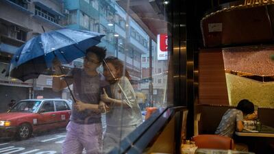 A couple walk in the heavy rain as a woman sits in a restaurant as Typhoon Haima makes landfall in Hong Kong. The usually frenetic streets of Hong Kong were deserted as the city went into lockdown for Typhoon Haima, which has killed at least eight people in the Philippines. Anthony Wallace / AFP