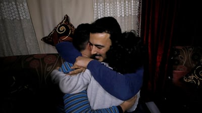 Amjad Yaghi hugs his younger brothers as he reunites with his mother. Reuters