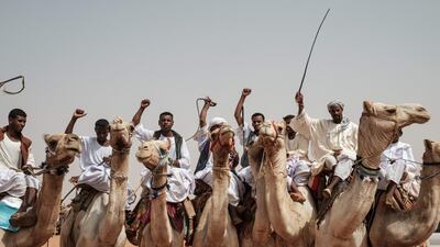 Men gesture while riding camels before a rally for supporters of Sudan's ruling Transitional Military Council (TMC) in the village of Abraq, about 60km northwest of Khartoum. AFP