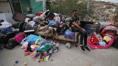 A Palestinian man sits next to the belongings of Rateb Hatab Shukairat, after the house in East Jerusalem was demolished by Israeli bulldozers. AFP