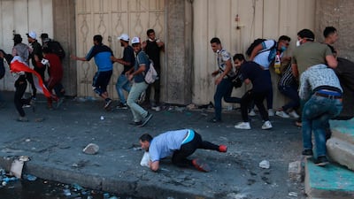 Anti-government protesters run for cover while security forces fire live ammunition in the air to disperse protesters, during ongoing protests, in Khilani Square, Iraq. AP Photo